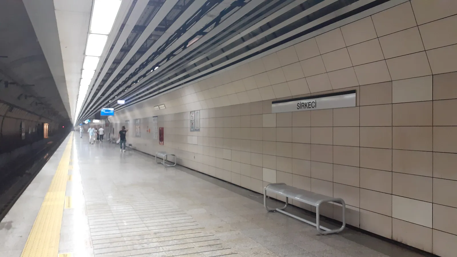 The underground Marmaray platform at Sirkeci in Istanbul, a long tiled corridor beside the track with the station name sign reading SİRKECİ on the wall
