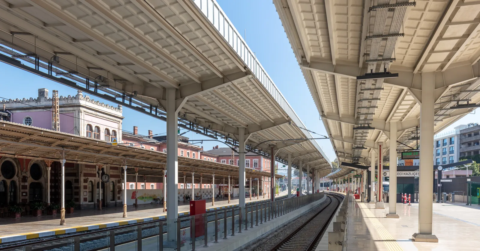 The platforms at Sirkeci station in Istanbul, long iron and glass canopies on slender columns running beside the track, with the brick and stone arcade of the 1890 terminal building along the left-hand side