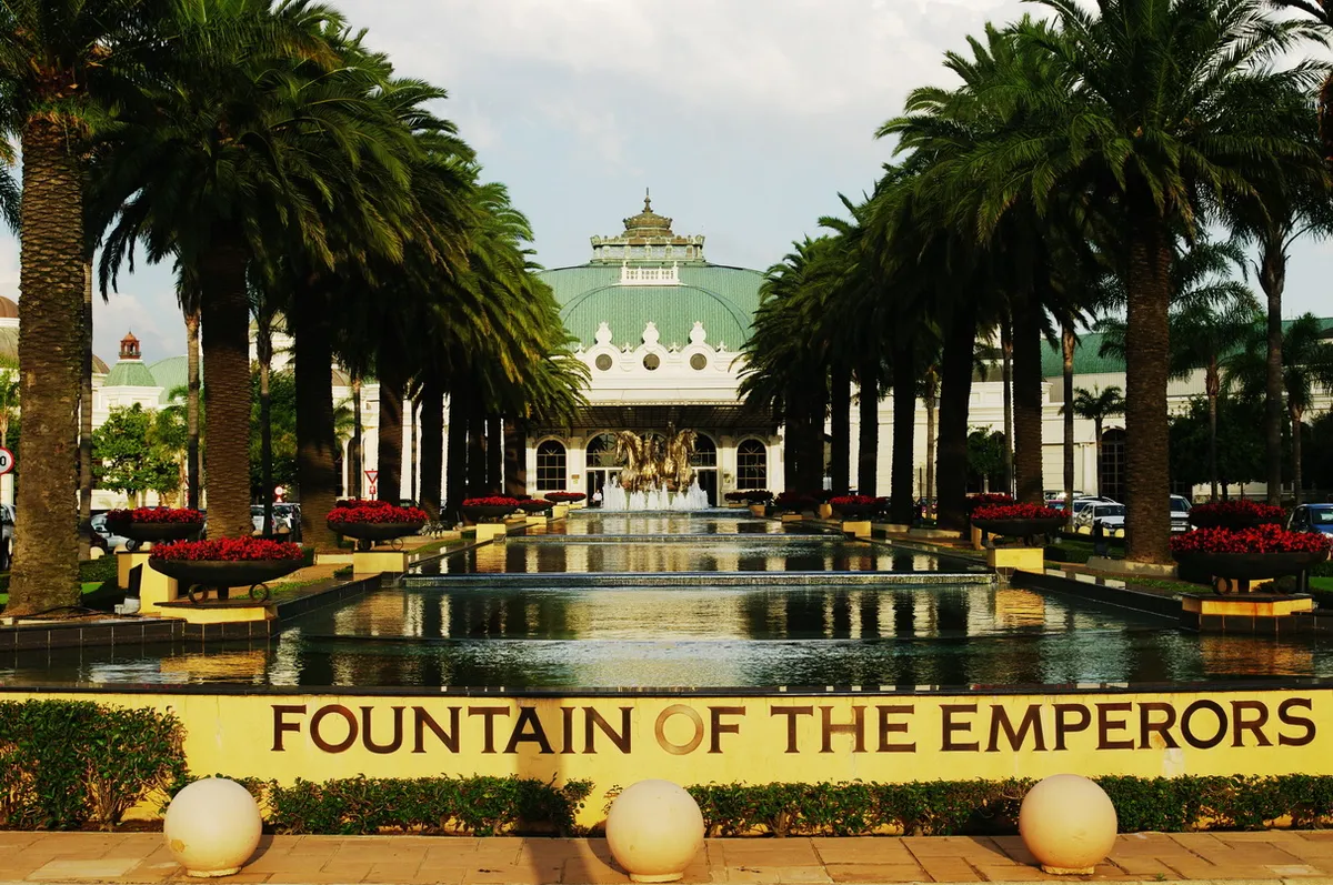 The Fountain of the Emperors at Emperors Palace in Kempton Park near Johannesburg, a long rectangular pool lined with palm trees leading to a domed and colonnaded entrance building