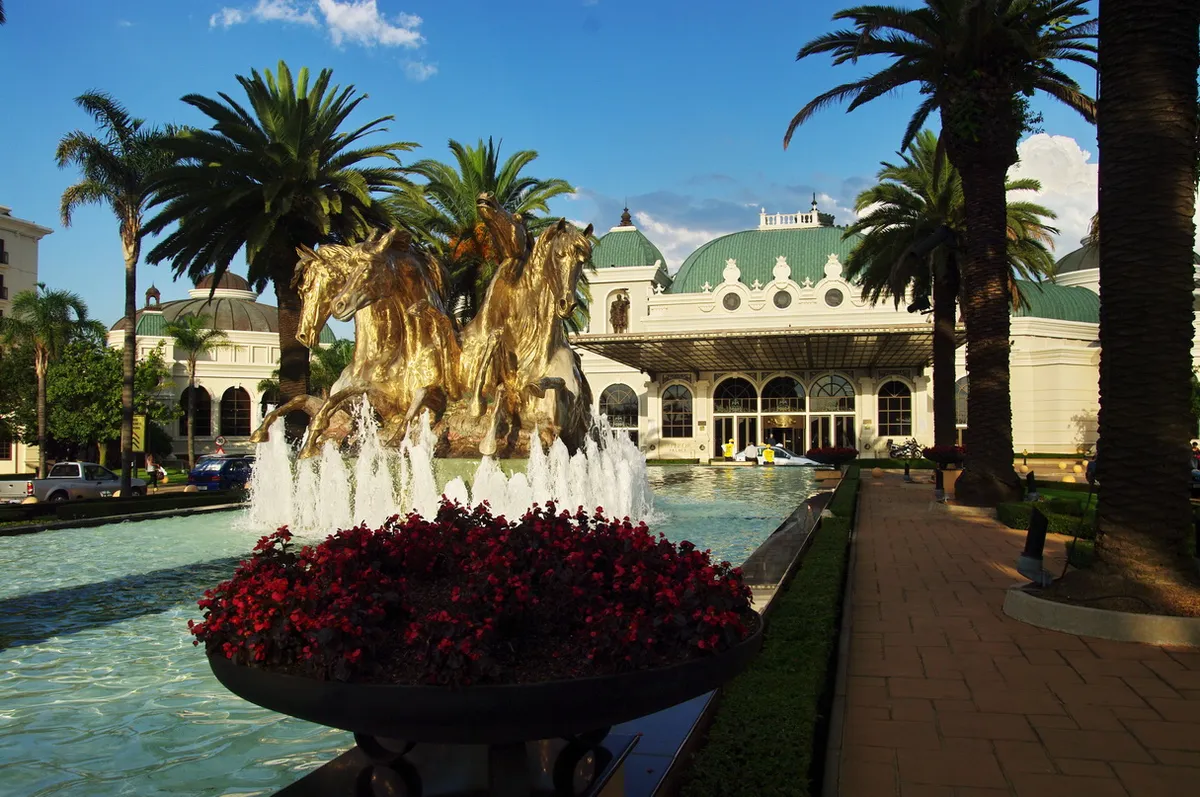The fountain court at Emperors Palace in Kempton Park, gilded horses rearing out of a long water channel with palms on either side and a green-domed colonnaded pavilion behind