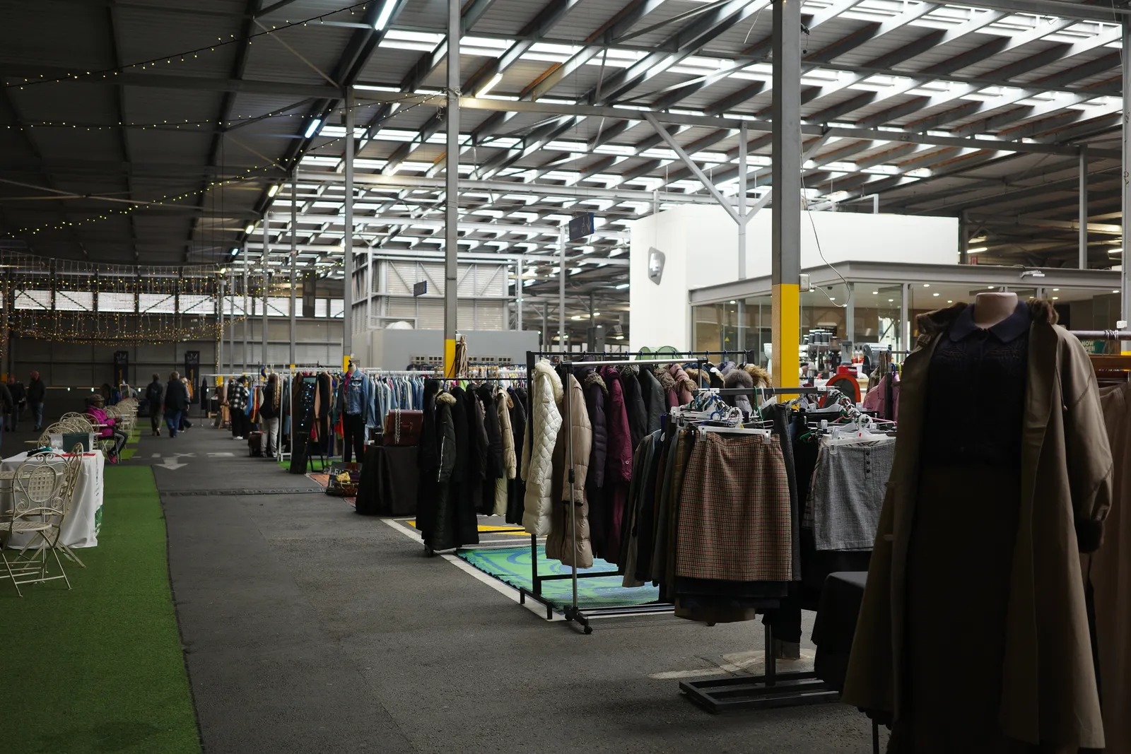 The Sunday market on the roof of Rosebank Mall in Johannesburg, rails of second-hand coats and dresses under a steel roof strung with lights, a strip of green matting running down the middle of the aisle
