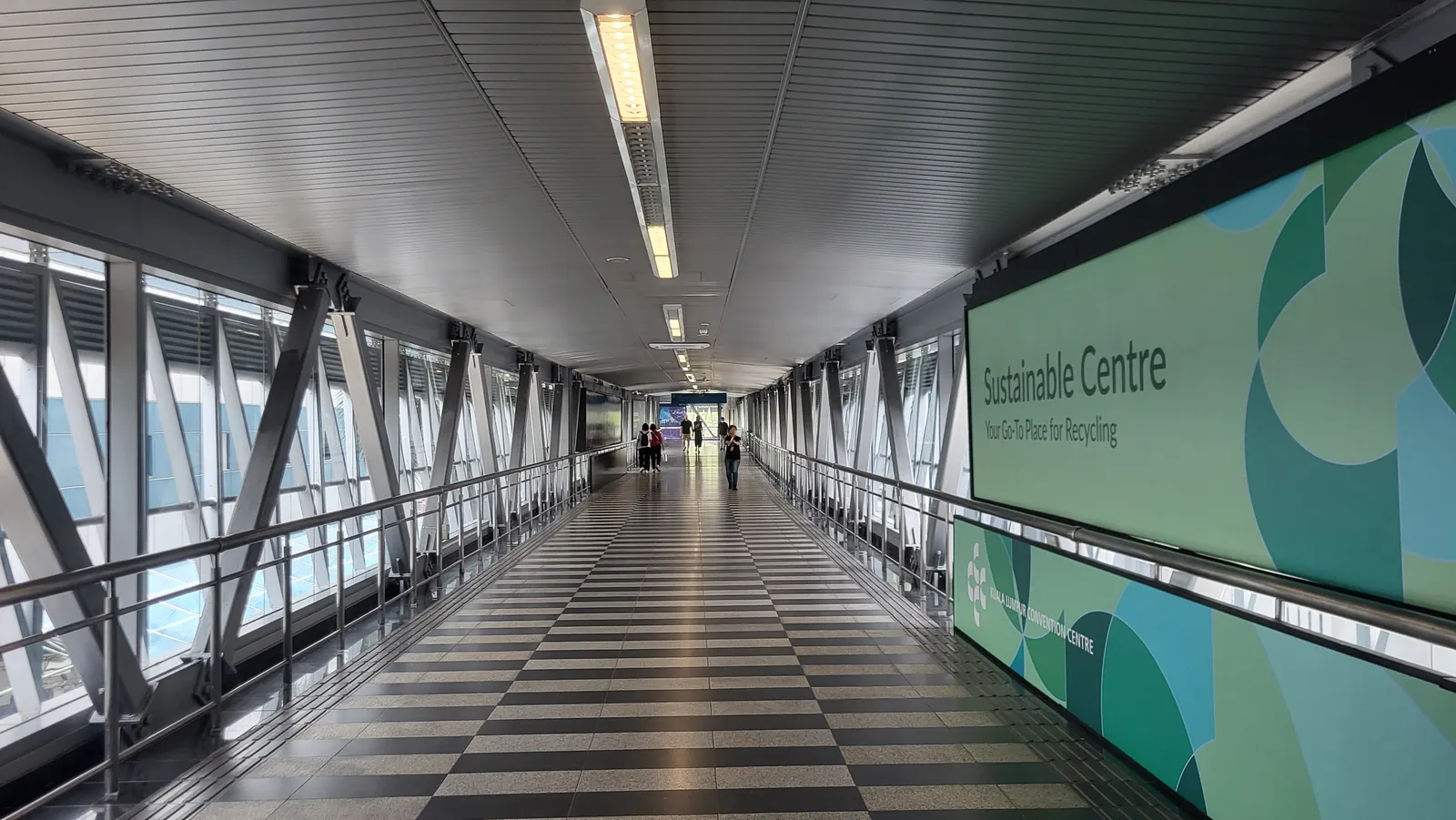 Inside the enclosed pedestrian walkway between Bukit Bintang and the Kuala Lumpur city centre, a long glazed tunnel with a chequered floor running away into the distance