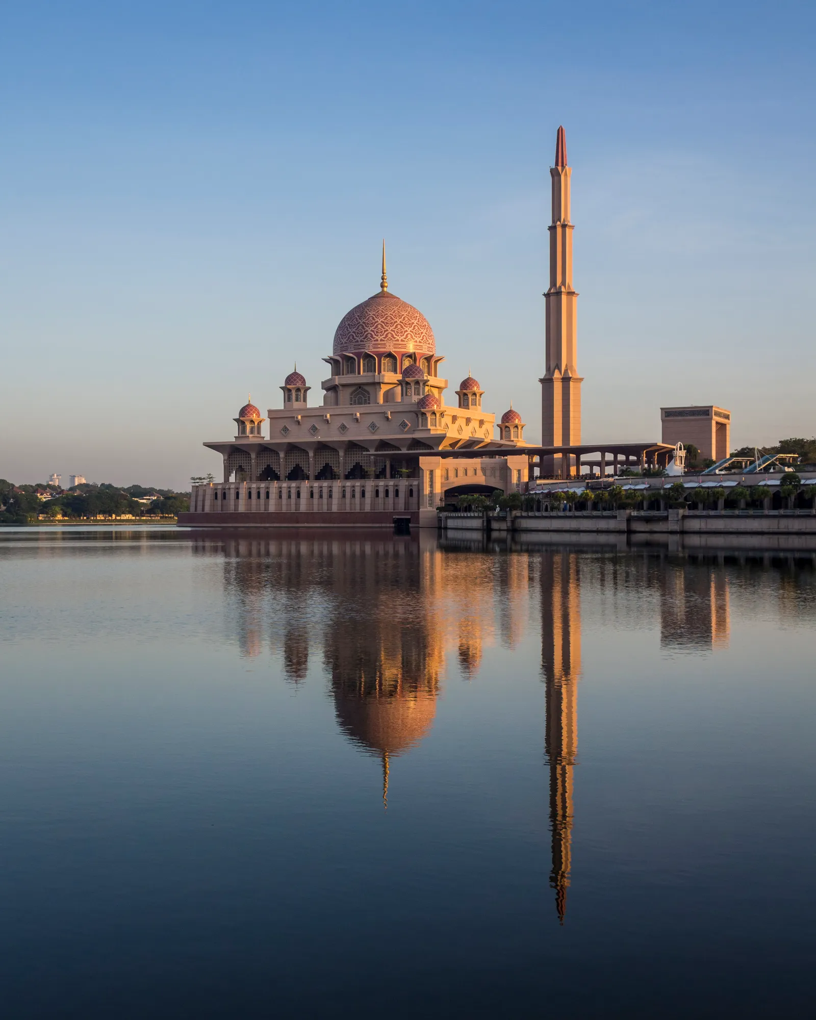 Putra Mosque in Putrajaya at first light, its rose-pink dome and single tall minaret reflected in the still water of the lake it stands on