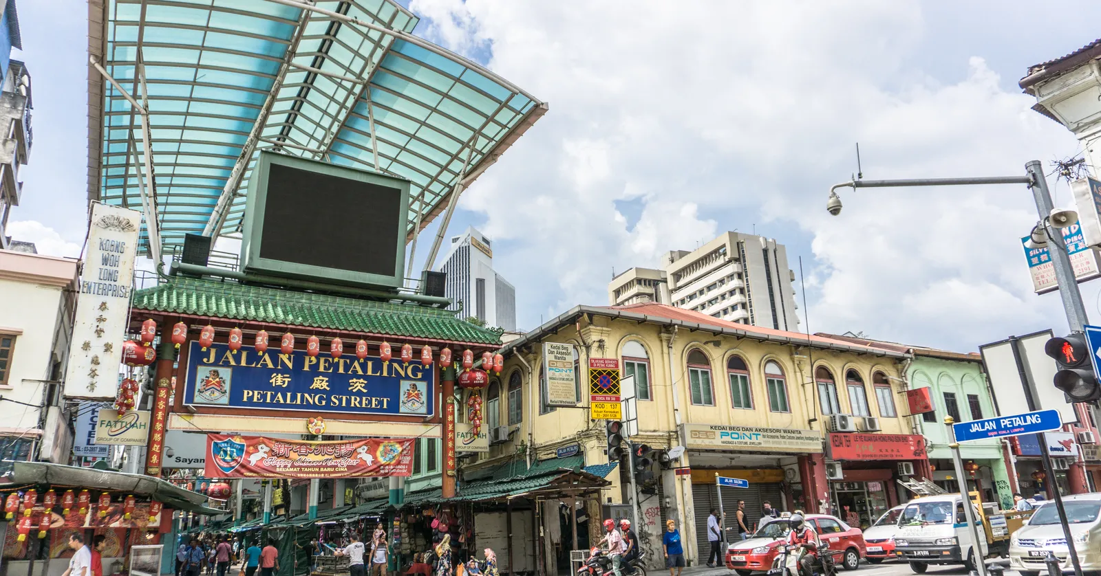The Chinese-style arch over the entrance to Jalan Petaling in Kuala Lumpur, its green canopy running away down the pedestrianised market street between shophouses