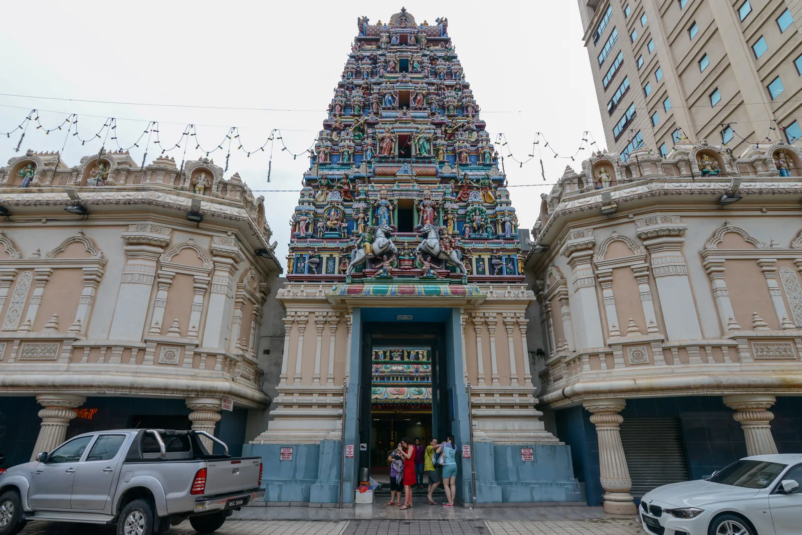The five-tier gate tower of Sri Mahamariamman Temple in Kuala Lumpur rising above its entrance, every level packed with brightly painted sculpted figures