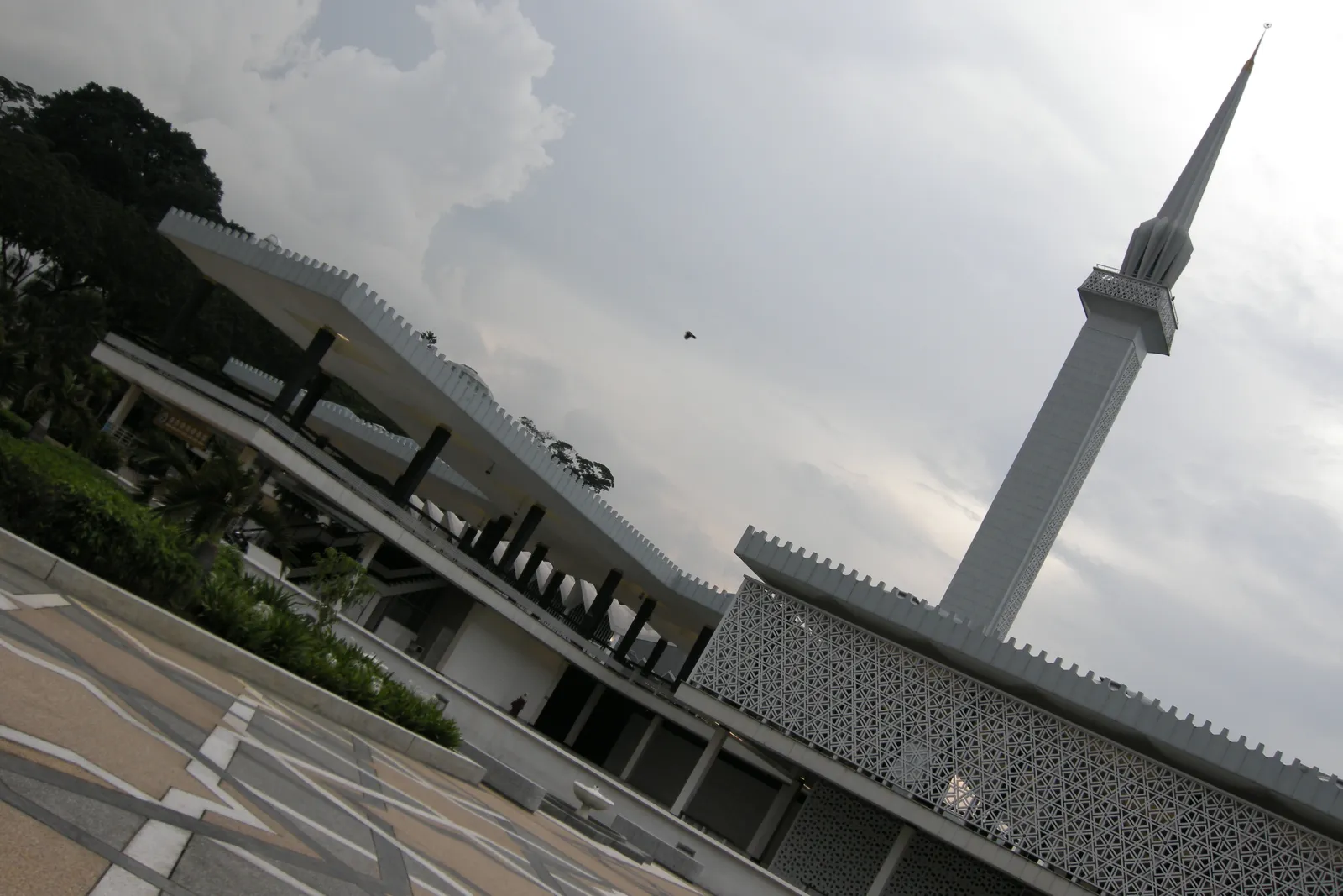 The National Mosque of Malaysia in Kuala Lumpur, its folded concrete roof spreading like an open umbrella over the prayer hall with the tall slim minaret standing beside it