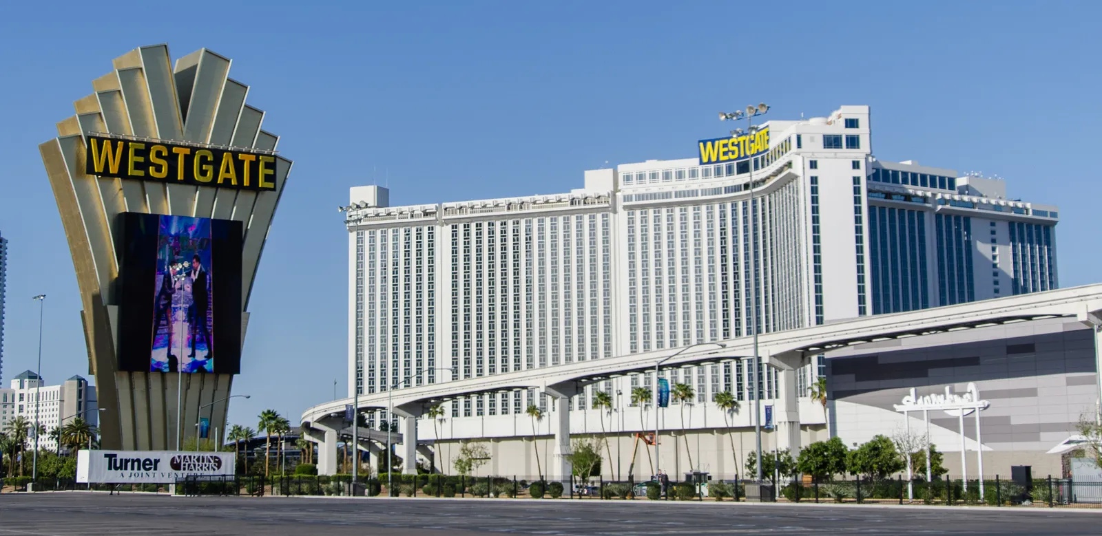 The Westgate Las Vegas resort, a long white tower block behind a gold marquee sign, with the elevated monorail guideway running across the frontage