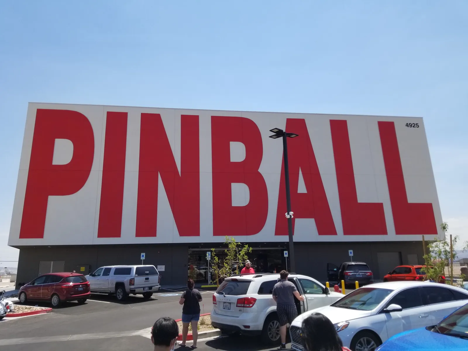 The Pinball Hall of Fame building on Las Vegas Boulevard, a plain white warehouse with PINBALL in enormous red capitals across the front and cars parked below