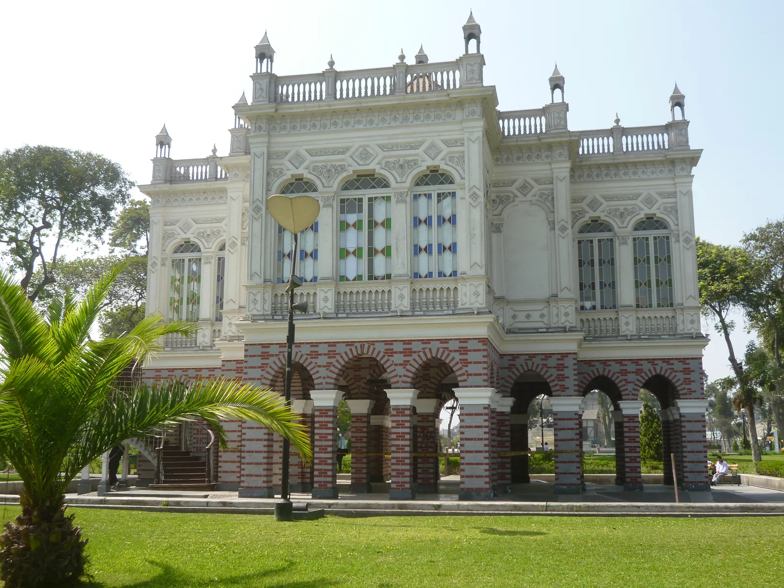 The Moorish pavilion in Lima's Parque de la Exposición, a white first floor of horseshoe windows above an arcade of red-and-white striped arches, with palms alongside
