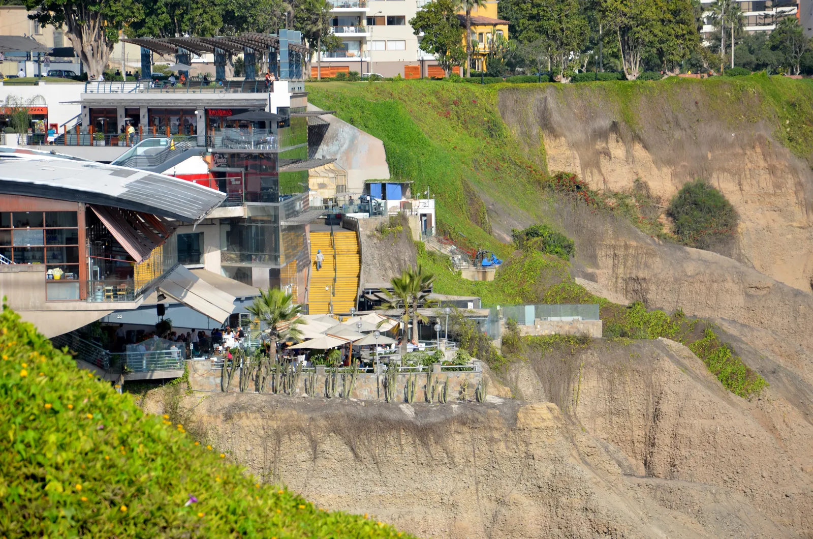 Larcomar's restaurant terraces stepping down the face of the Miraflores cliff in Lima, with the bare eroded cliff wall rising alongside them