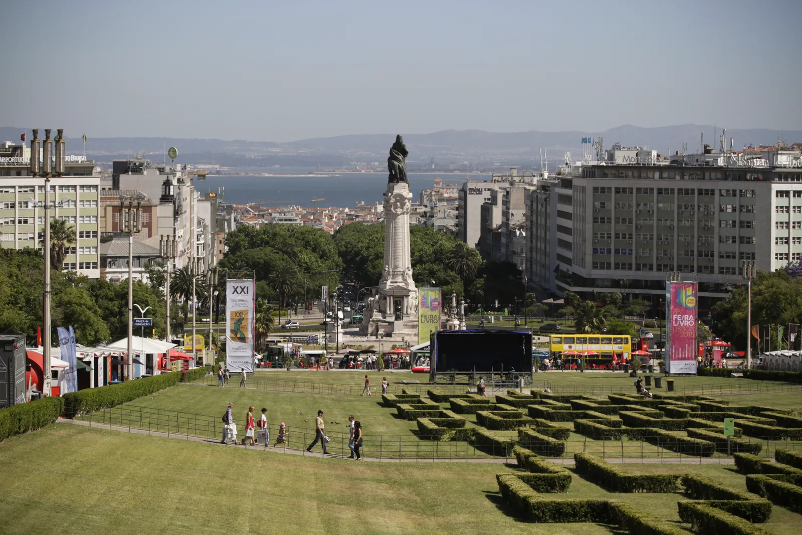 The view down Parque Eduardo VII in Lisbon over clipped box hedges to the column on Marquês de Pombal square, with the city and the Tagus estuary beyond
