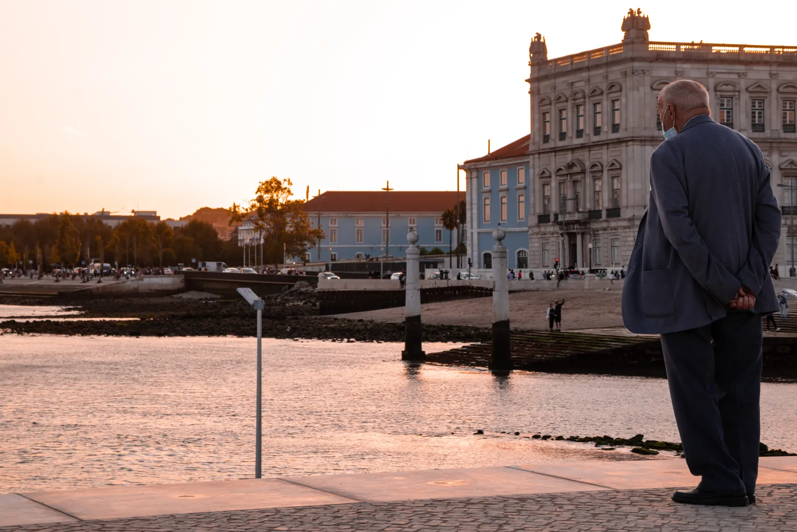 The stone ramp at Ribeira das Naus in Lisbon sloping into the Tagus at sunset, with the old naval arsenal buildings along the waterfront behind