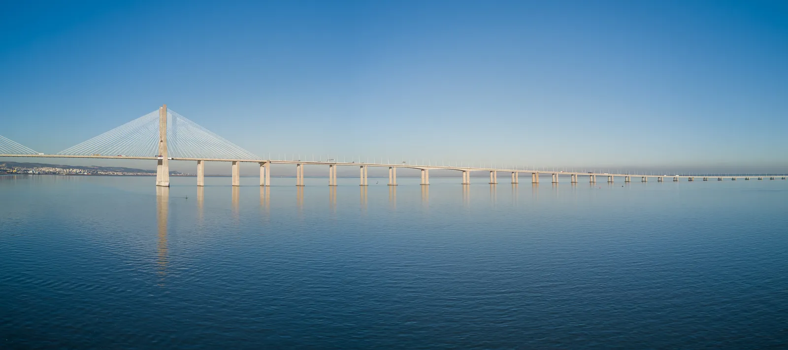 The Vasco da Gama bridge stretching across the flat water of the Tagus estuary near Lisbon until it disappears at the horizon