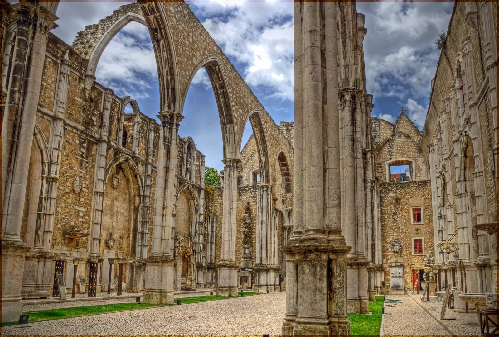 The roofless Gothic nave of the Carmo Convent in Lisbon, its pointed arches standing open to the sky above a gravel floor