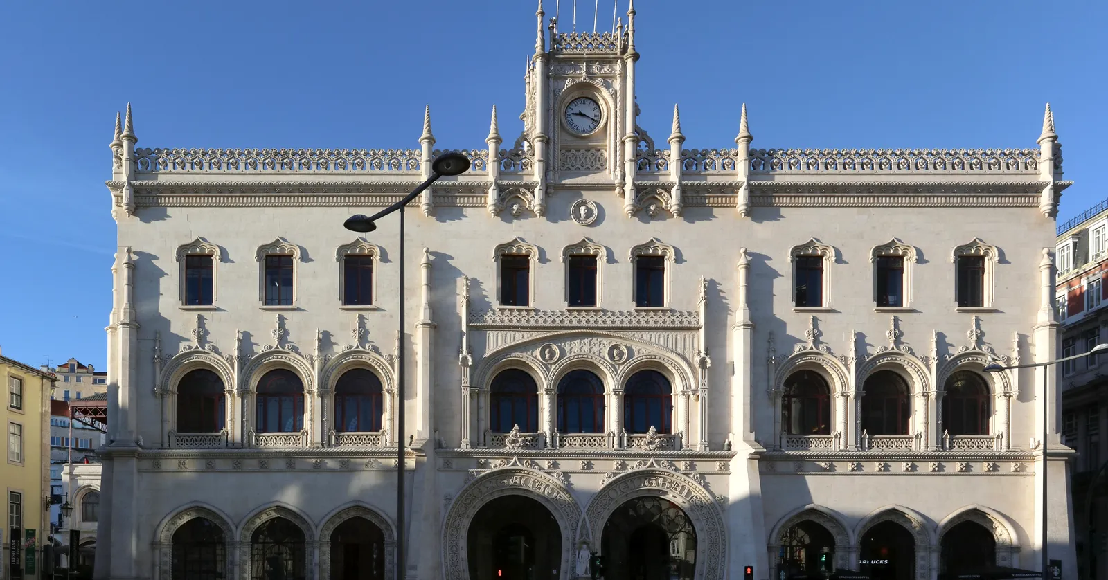 The white neo-Manueline front of Rossio station in Lisbon, with two interlocking horseshoe-arch doorways below a clock tower