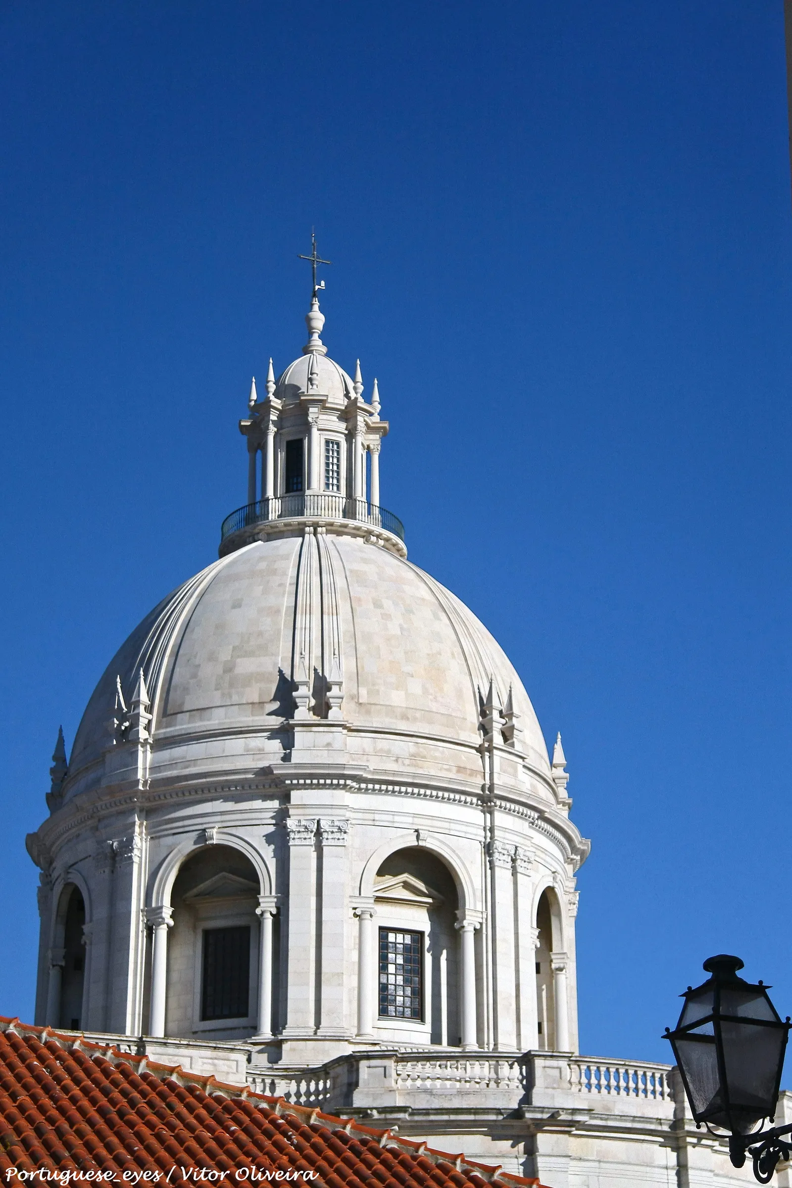 The white marble dome of the National Pantheon in Lisbon rising above red terracotta rooftops against a deep blue sky
