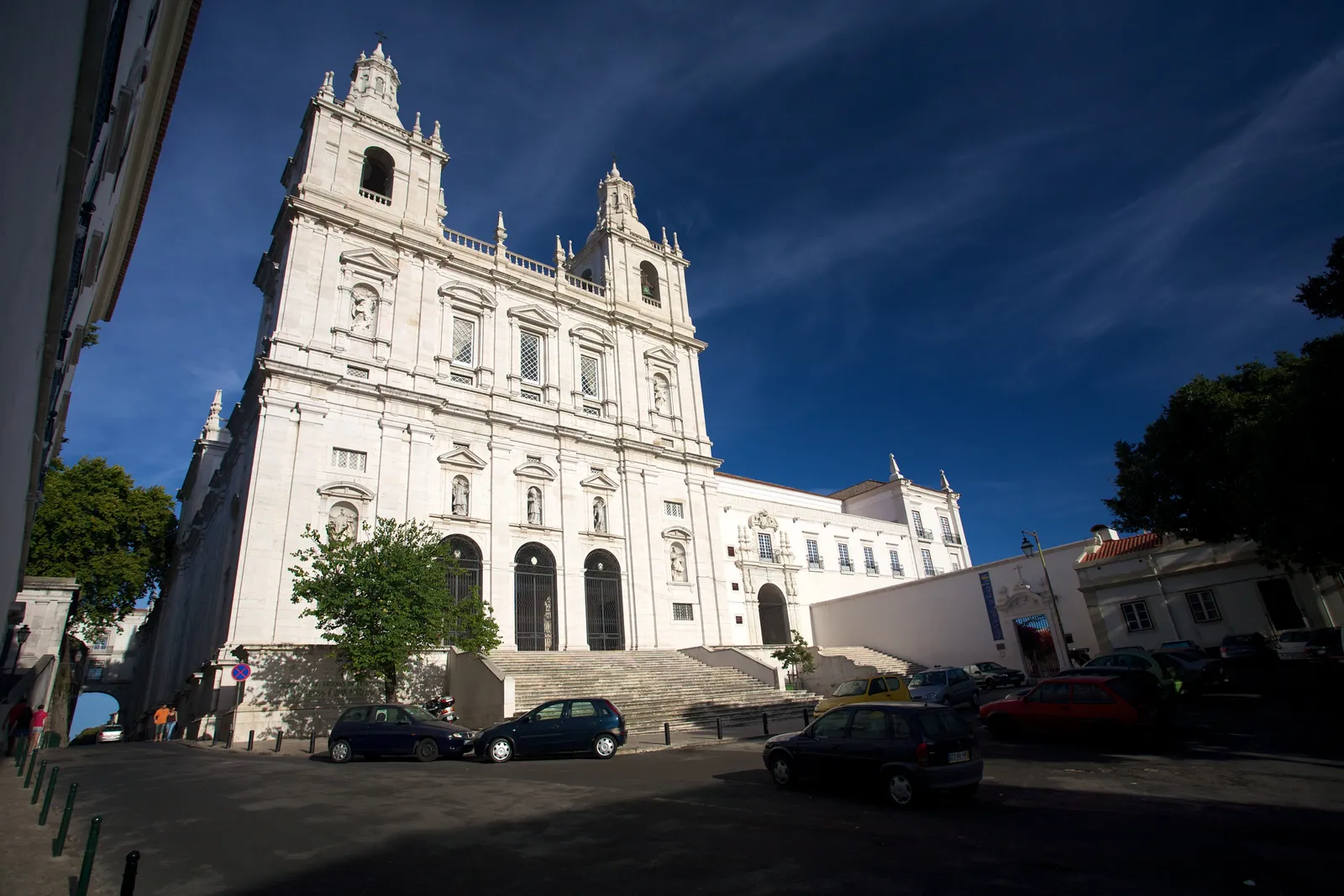 The white twin-towered facade of the São Vicente de Fora monastery in Lisbon, seen across the small square in front of it