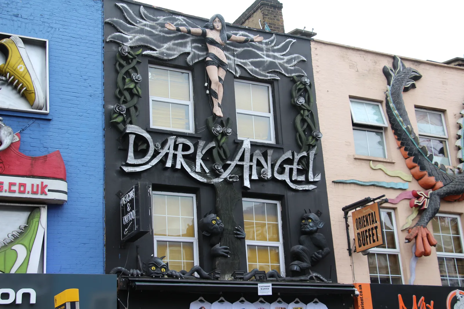 Elaborate oversized shopfronts, including a giant sneaker and dragon facade, along Camden High Street