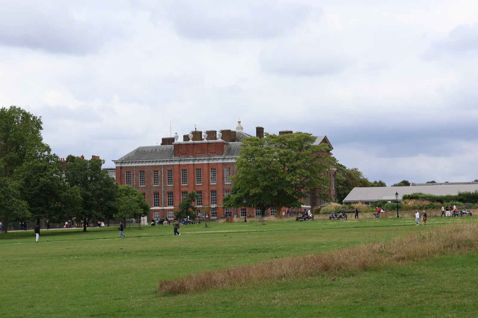 The red-brick front of Kensington Palace in London seen across the open lawns of Kensington Gardens