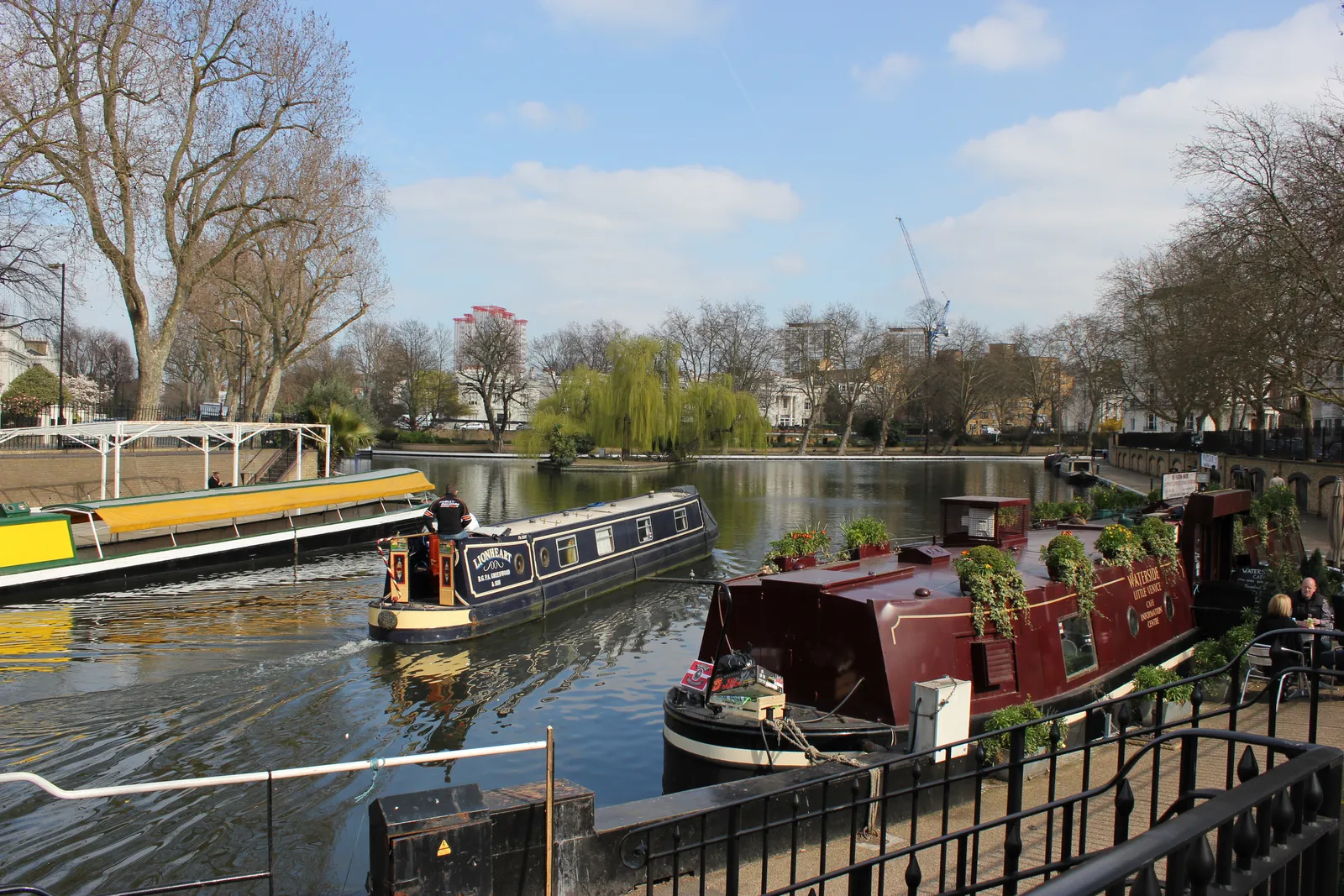 Painted narrowboats moored on the canal basin at Little Venice in London, with willow trees along the water