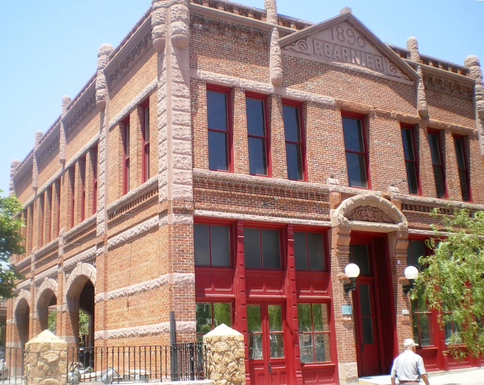 The Garnier Building in Los Angeles, a two-storey red brick corner block with arched windows picked out in dark red paint and the date 1890 carved into the stone pediment above the roofline