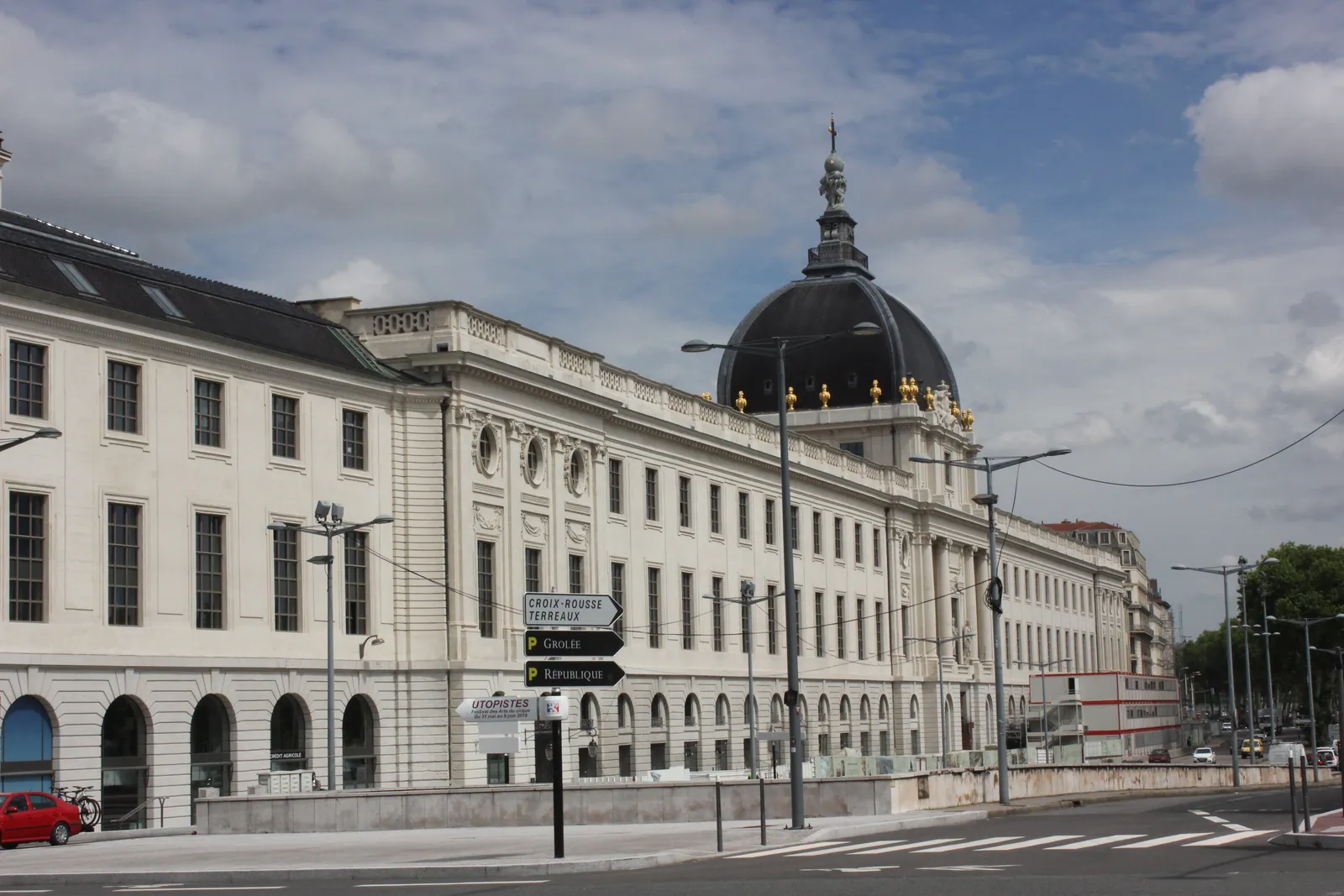 The Grand Hôtel-Dieu in Lyon from the riverside, a long pale classical facade running down the quay with a dark domed lantern rising over its centre