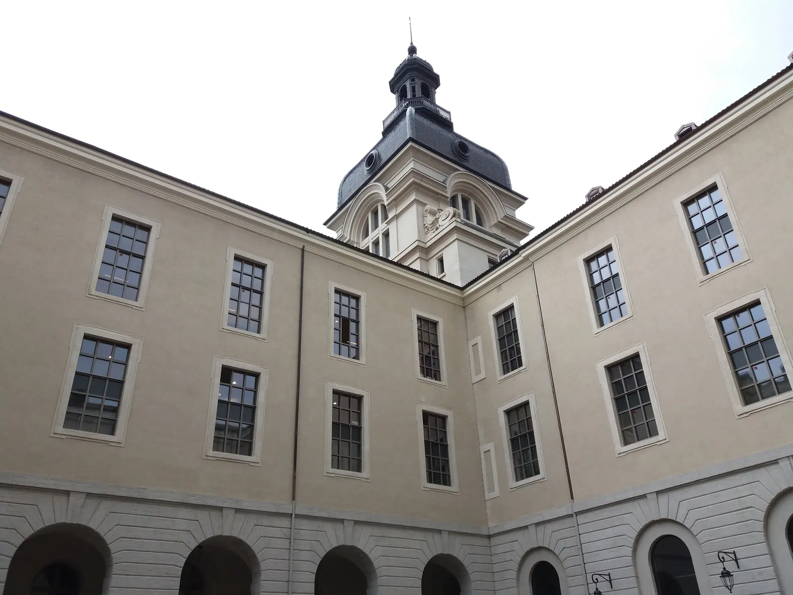 One of the inner courtyards of the Grand Hôtel-Dieu in Lyon, plain rendered walls with rows of tall windows on three sides and the lantern of the dome rising above the far range