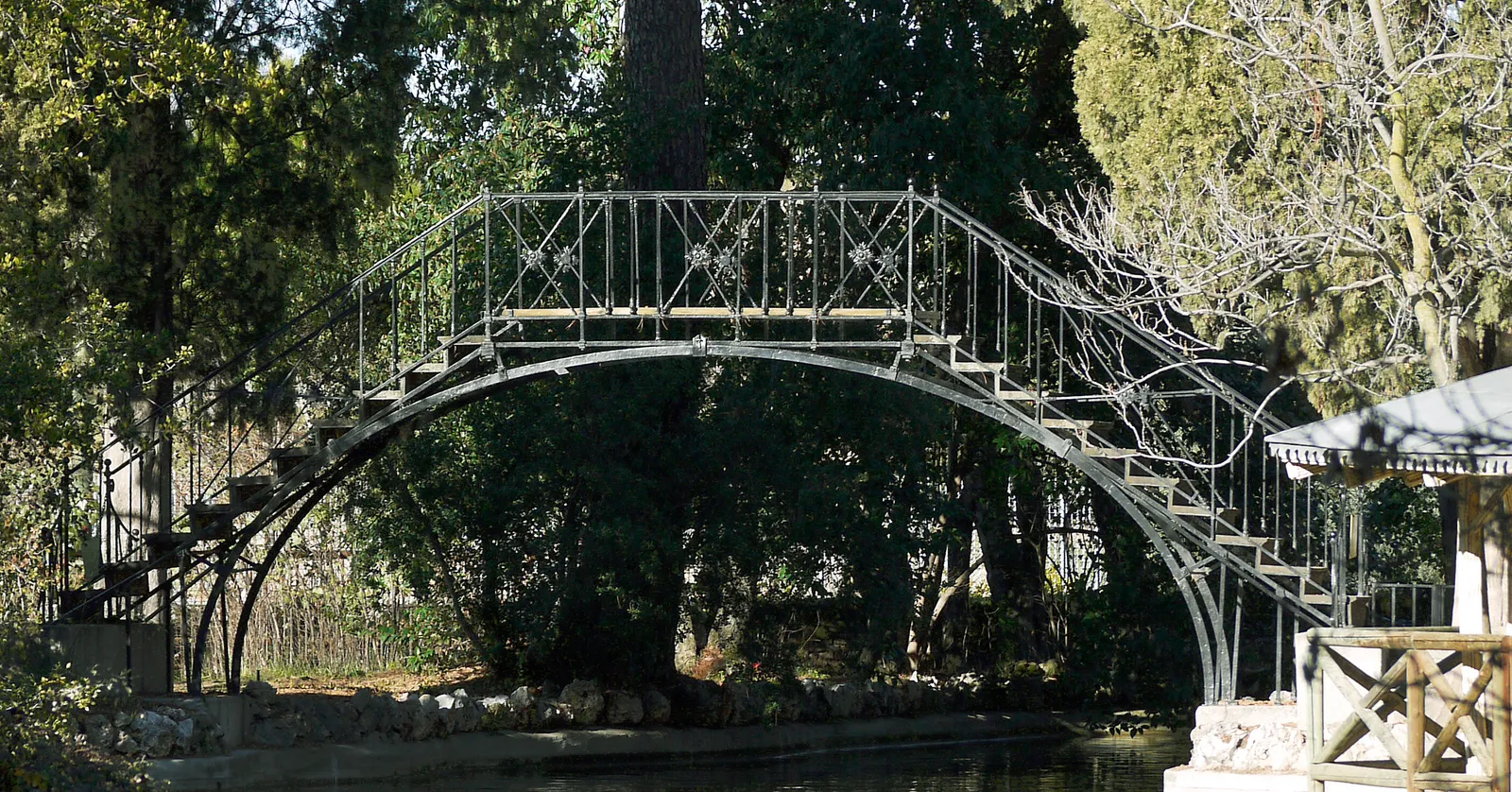 An iron footbridge over the water inside El Capricho park in Madrid