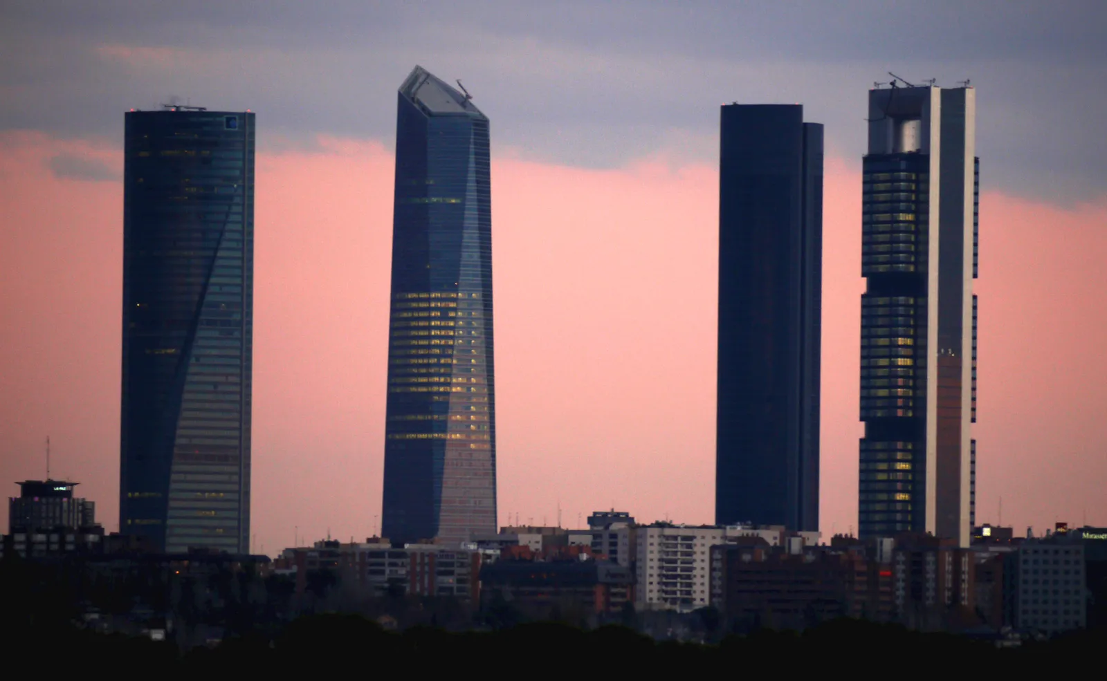 The four Cuatro Torres skyscrapers rising above northern Madrid against a pink evening sky