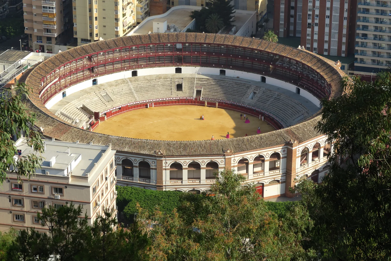 An aerial view of the circular Plaza de Toros de La Malagueta bullring in Málaga, surrounded by apartment buildings
