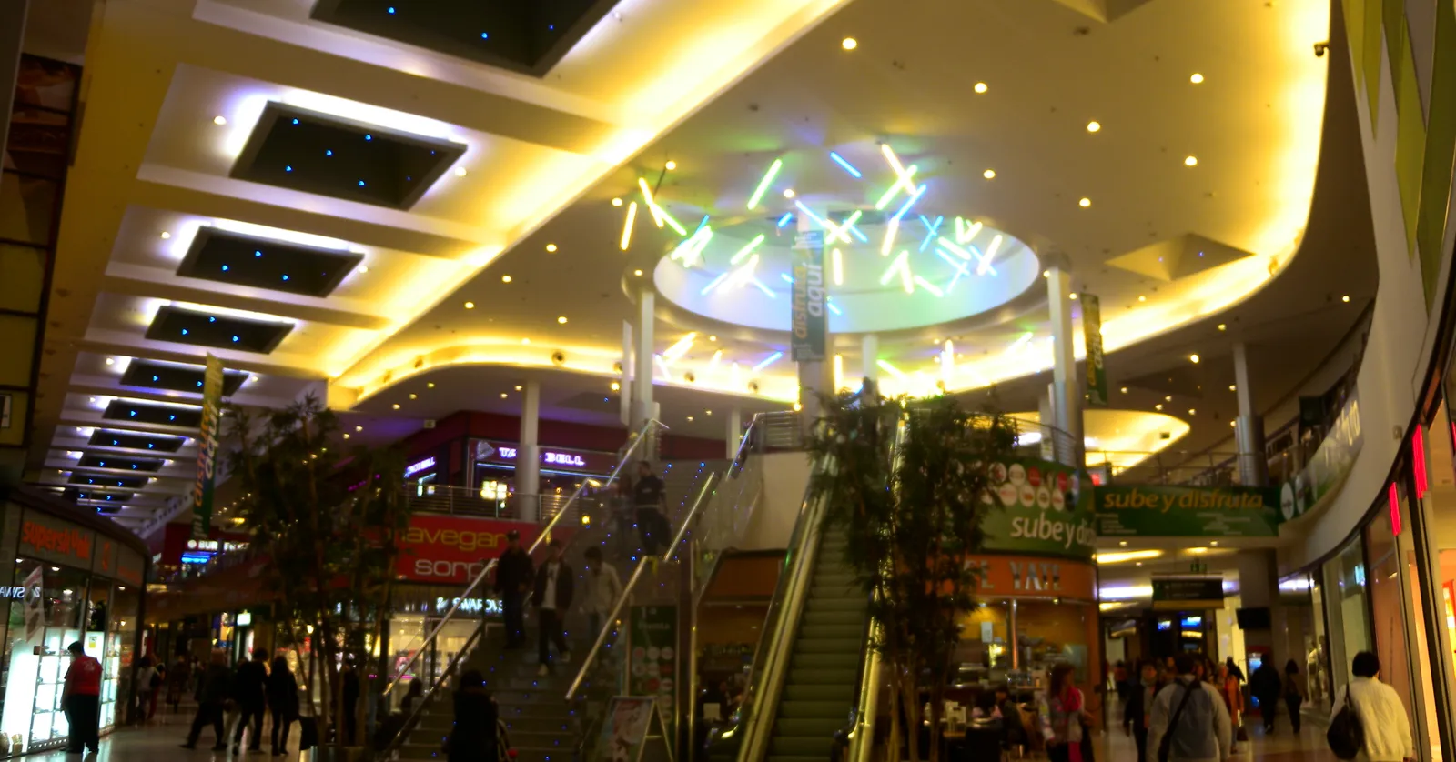 The bright, multi-level interior of Vialia shopping centre inside Málaga María Zambrano station, with escalators and storefronts
