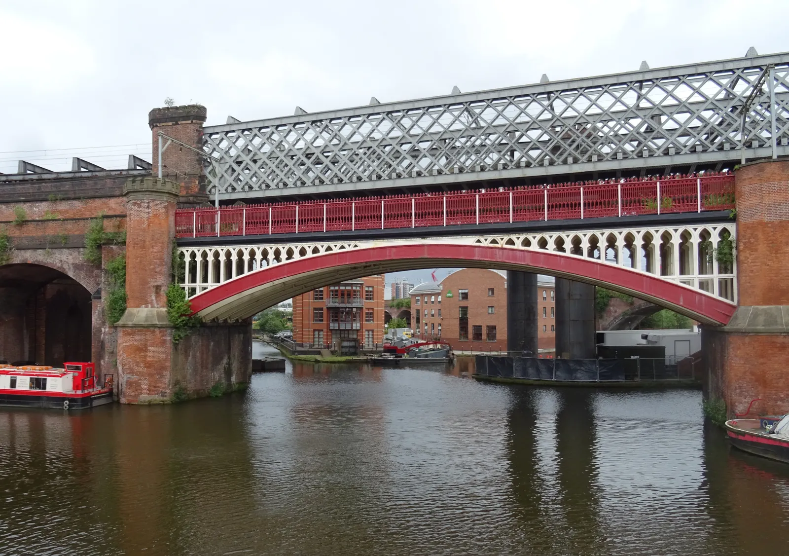 Red-brick railway viaducts crossing the canal basin at Castlefield in Manchester, with narrowboats moored below