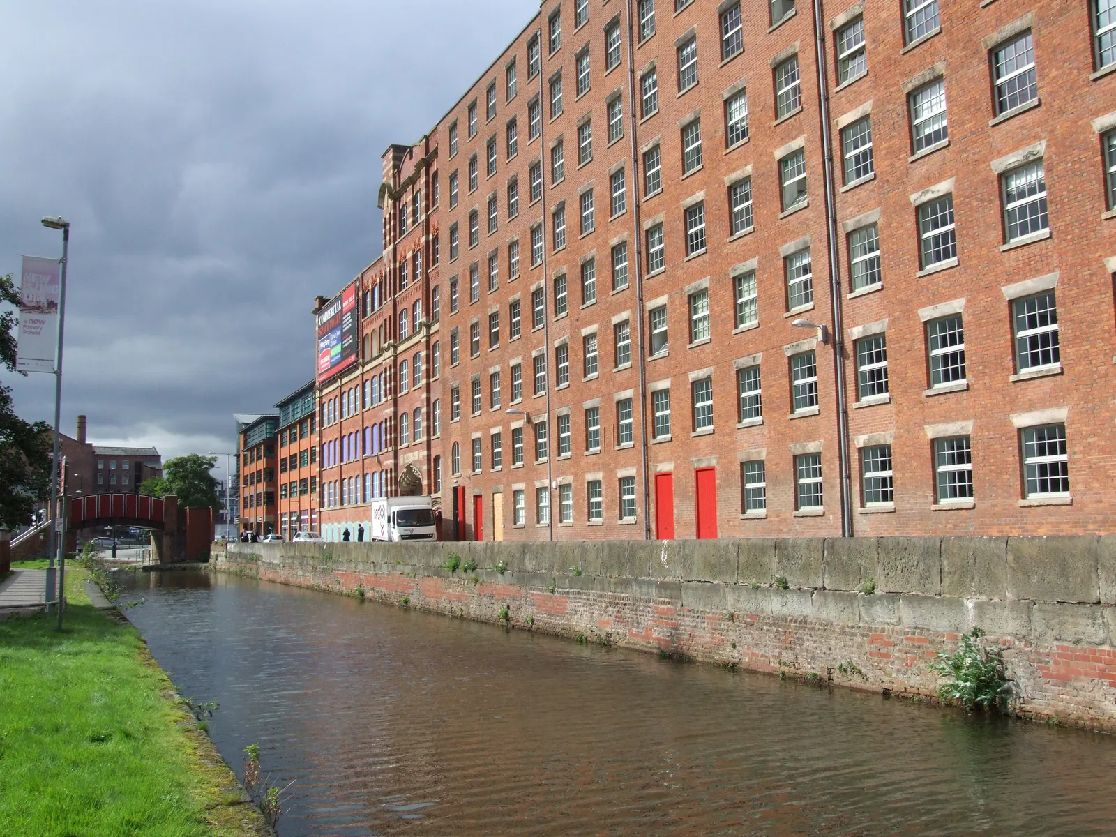 A row of red-brick Victorian cotton mills beside the Rochdale Canal on Redhill Street in Ancoats, Manchester