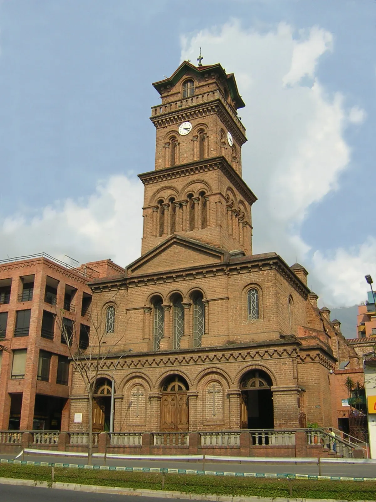 The brick Romanesque bell tower and clock of Iglesia San José del Poblado in Medellín, seen from the street below
