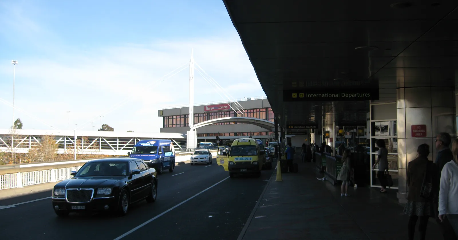 The departures drive outside Melbourne Airport's international terminal, cars and taxis pulling in under a long concrete canopy with an International Departures sign above the doors