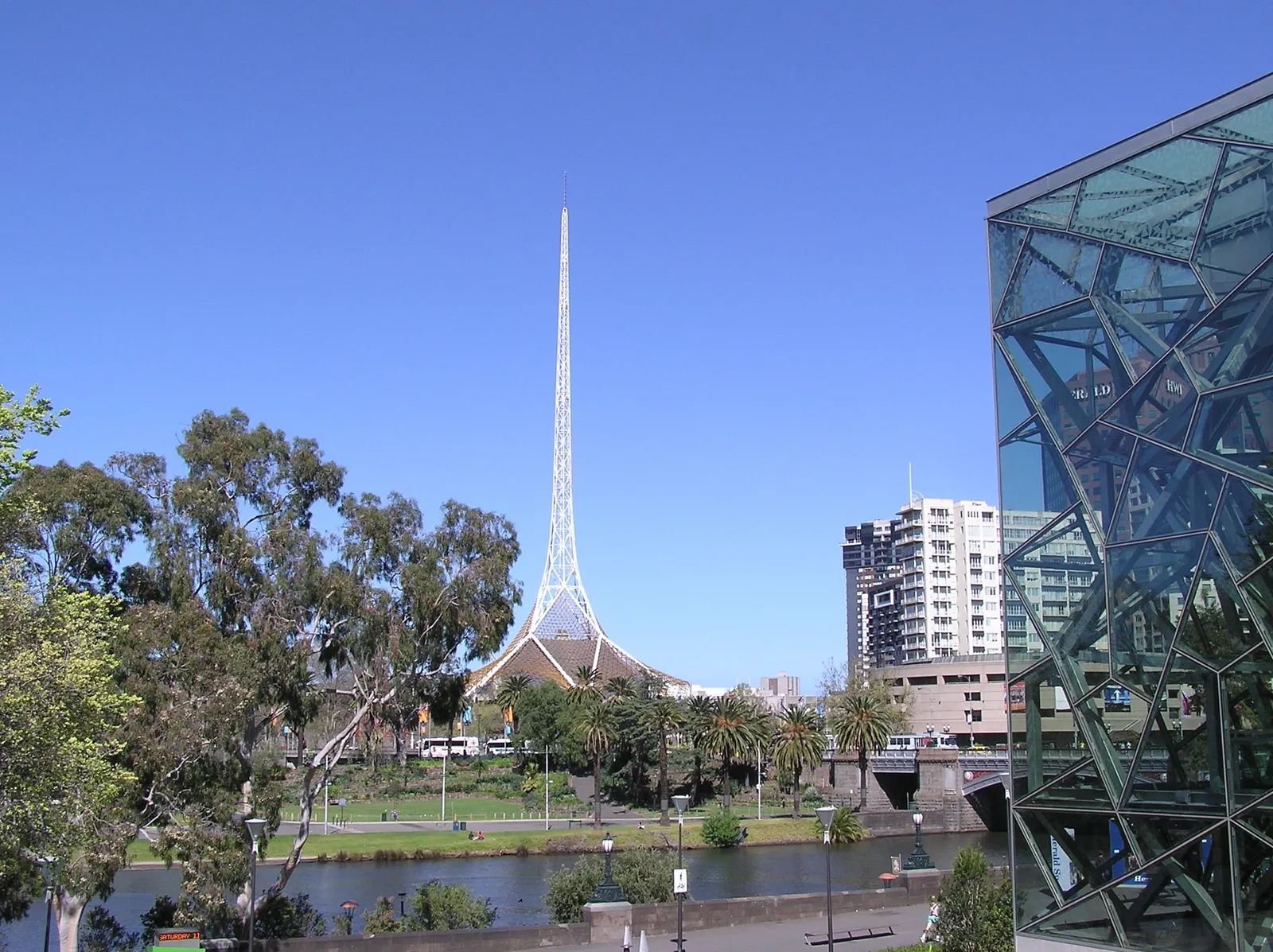 The white lattice spire of Arts Centre Melbourne rising above the theatres building on St Kilda Road, seen across the Yarra from Federation Square