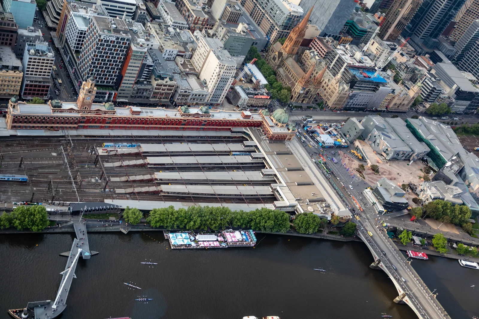 Looking straight down from Melbourne Skydeck onto the platform canopies of Flinders Street Station, the Yarra River and the footbridges crossing it