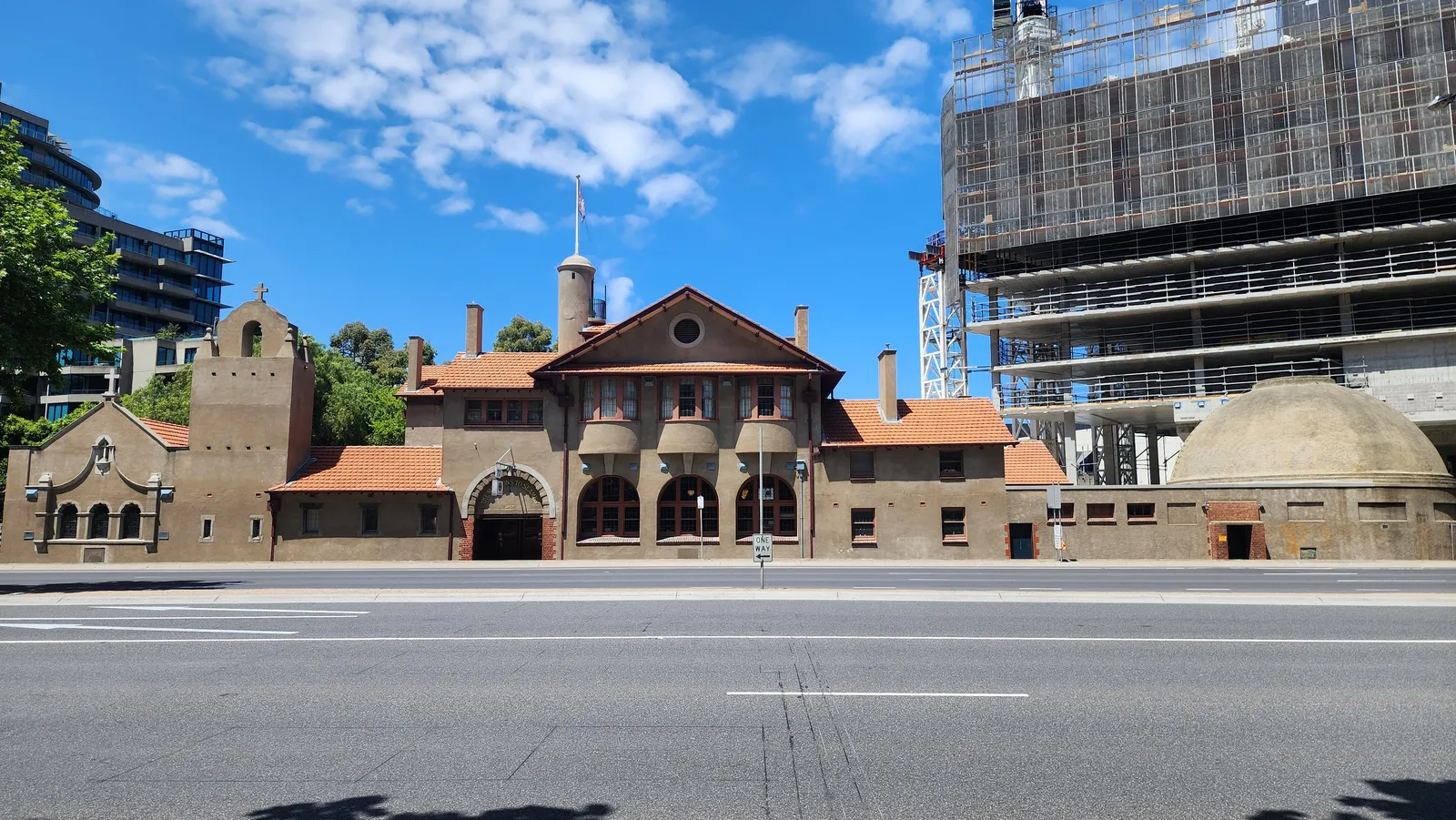 The Mission to Seafarers building on Flinders Street in Melbourne, a low red-tiled Arts and Crafts complex with an arched entrance, a squat tower and a domed brick roof at its right-hand end