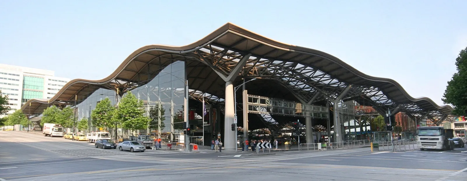 The undulating steel and glass roof of Southern Cross Station in Melbourne seen from Spencer Street, its wave form running the length of the frontage over the entrance