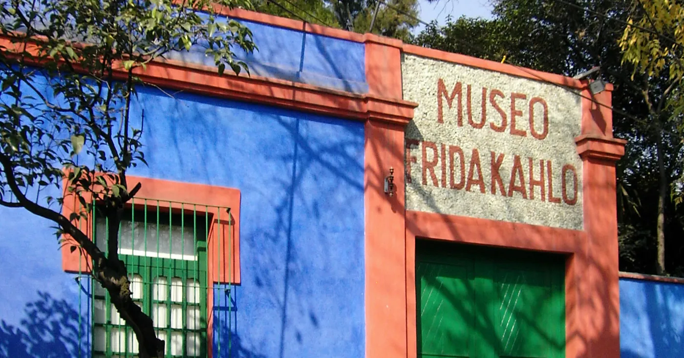 The cobalt blue and red-trimmed corner wall of the Casa Azul in Coyoacán, Mexico City, with Museo Frida Kahlo lettered in mosaic above the entrance