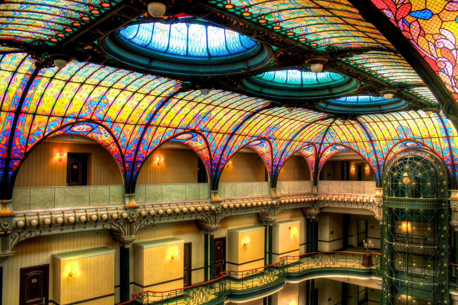 The curved stained-glass ceiling over the lobby of the Gran Hotel Ciudad de México, a barrel vault of coloured glass in floral patterns above tiers of iron balconies