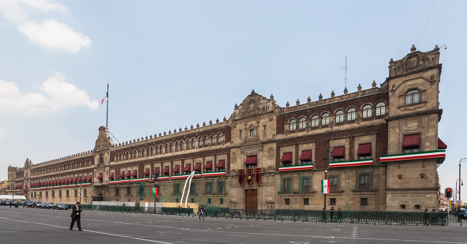 The long red tezontle and pale stone front of the Palacio Nacional running the whole east side of Mexico City's Zócalo, with the national flag flying above its central balcony