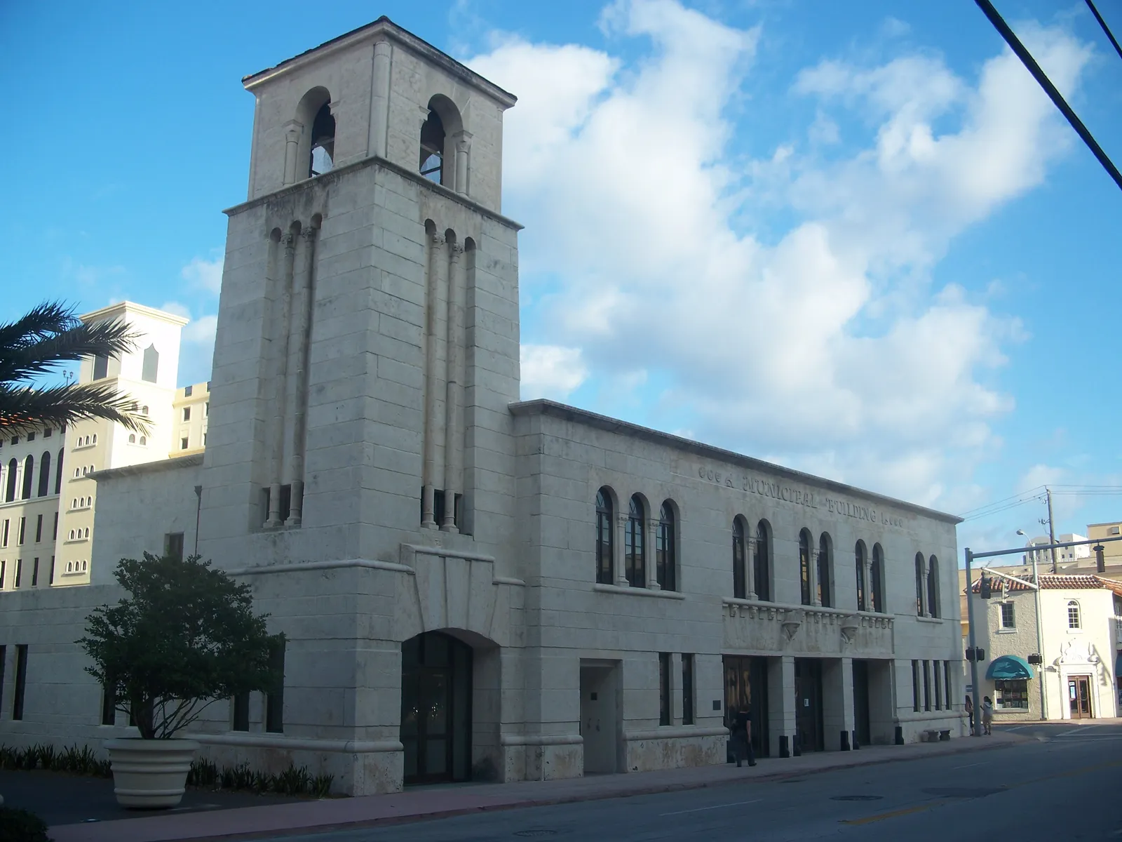 The Coral Gables Museum in Miami, the former 1939 police and fire station, a pale coral-rock building with a square tower over an arched doorway and a row of tall windows along the street