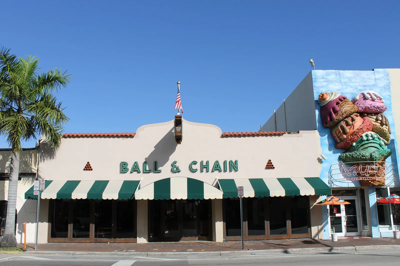 The front of Ball & Chain on Calle Ocho in Little Havana, Miami, a low cream building with a green-and-white striped awning and the bar's name in green letters above it