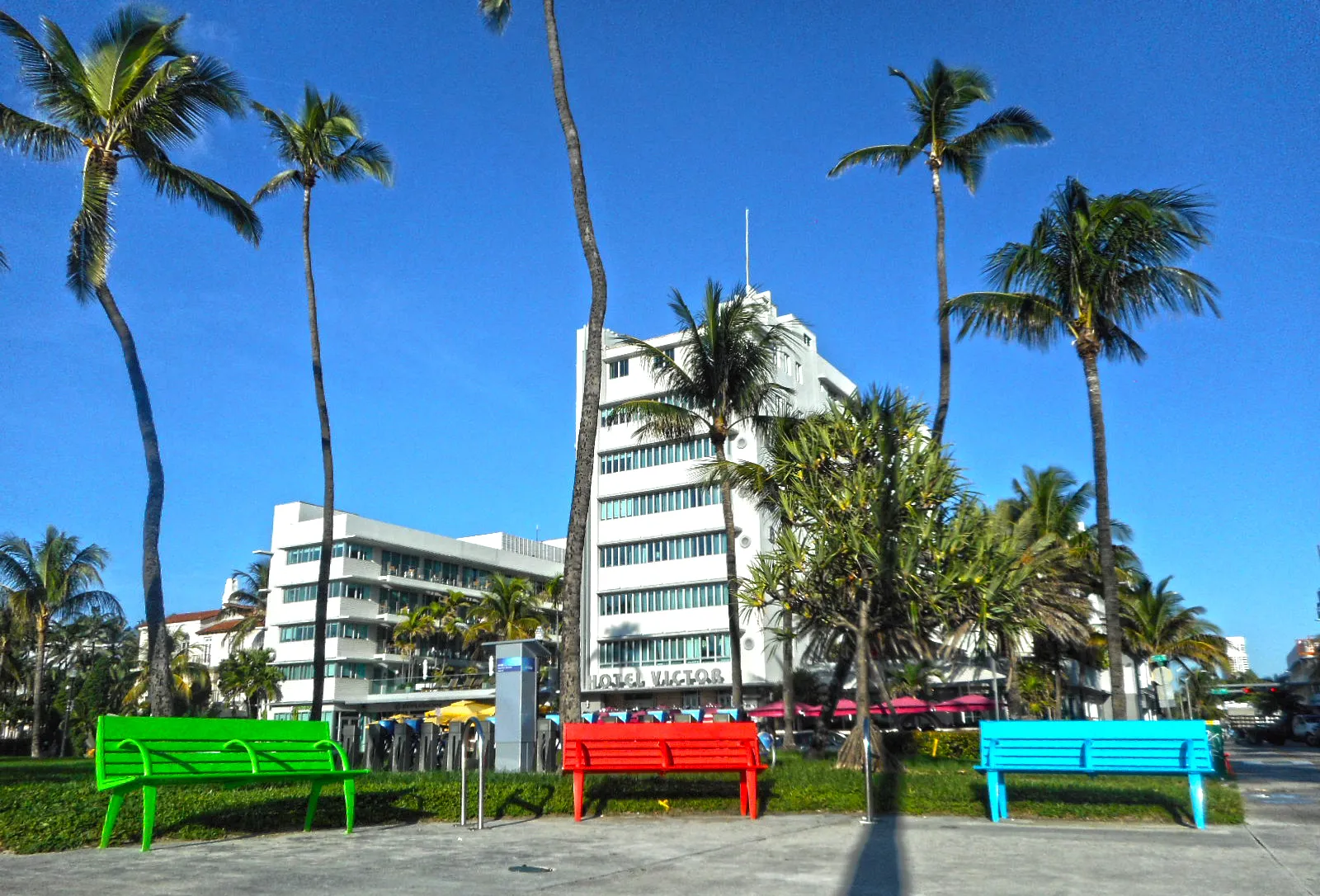 Colorful benches and palm trees in Lummus Park in South Beach, with the Art Deco Hotel Victor behind