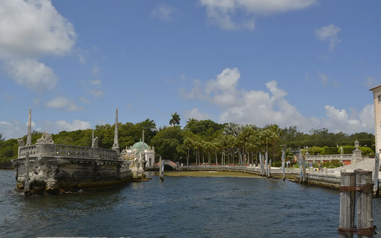 The carved stone barge in Biscayne Bay just off Vizcaya's waterfront terrace in Miami, a weathered breakwater shaped like a ship, with mangroves and palms along the shore behind