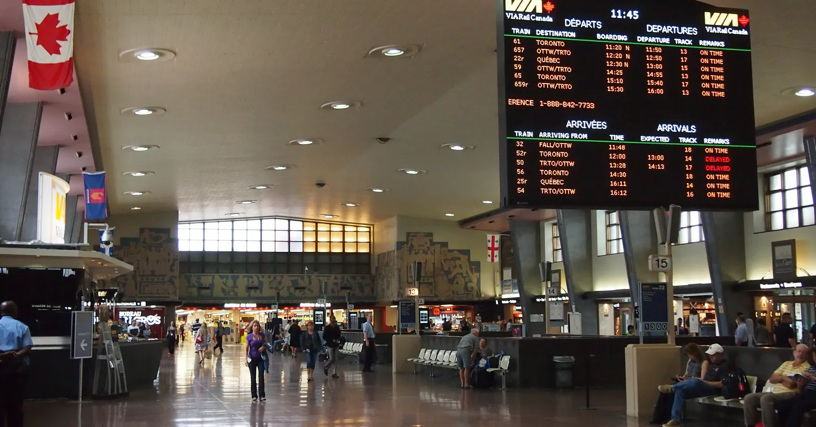The concourse of Gare Centrale in Montreal, with a large departures board hanging over the floor, a Canadian flag to one side and carved stone friezes running along the upper walls
