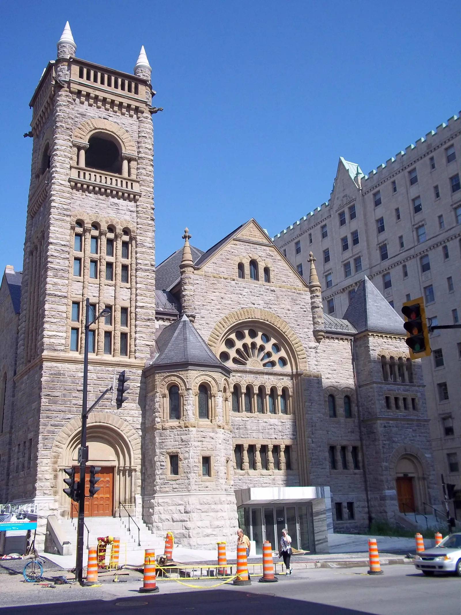 The grey stone Romanesque Revival church that now houses Bourgie Hall in Montreal, a square corner tower beside a gabled front with a large round window over the entrance arch