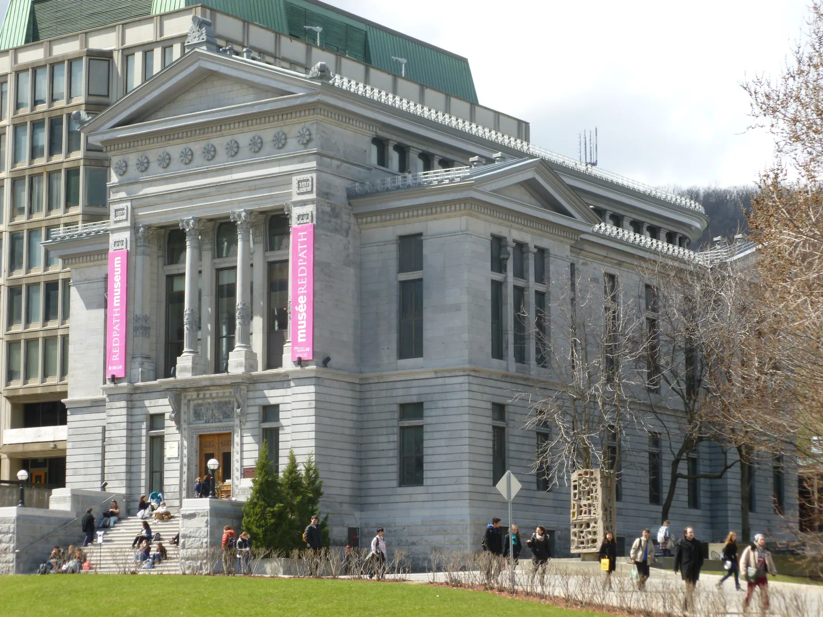 The Redpath Museum on the McGill University campus in Montreal, a grey stone building with a columned portico under a triangular pediment, students sitting on the steps outside
