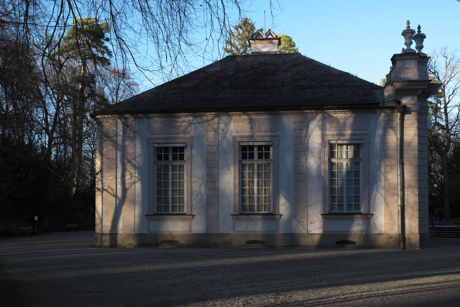 The Amalienburg hunting lodge in Nymphenburg's park, a low cream-coloured pavilion with tall arched windows and a hipped roof, seen from the front on a winter afternoon
